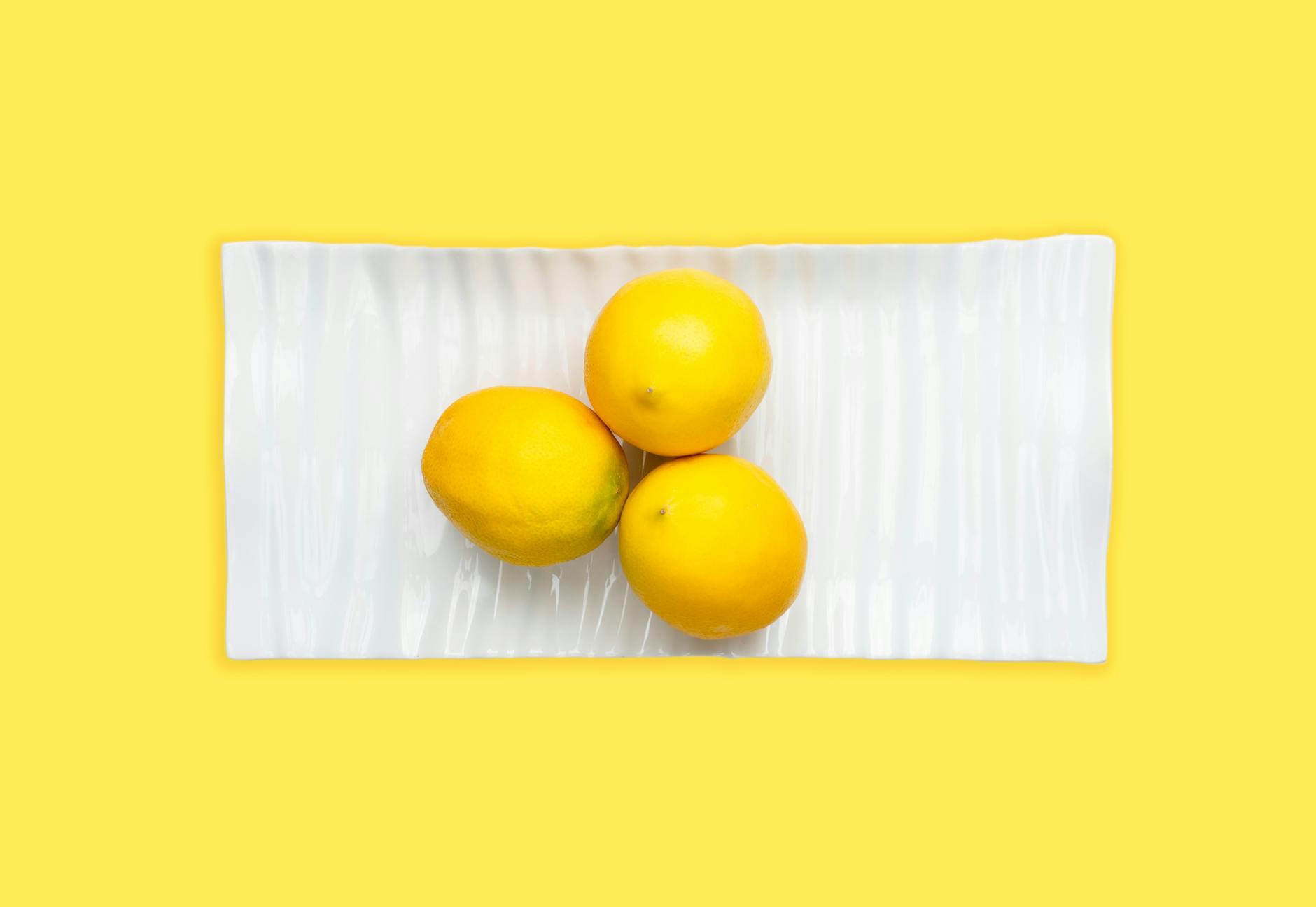 Fresh lemons on white plate with yellow background, symbolizing vitality and pleasure at any age