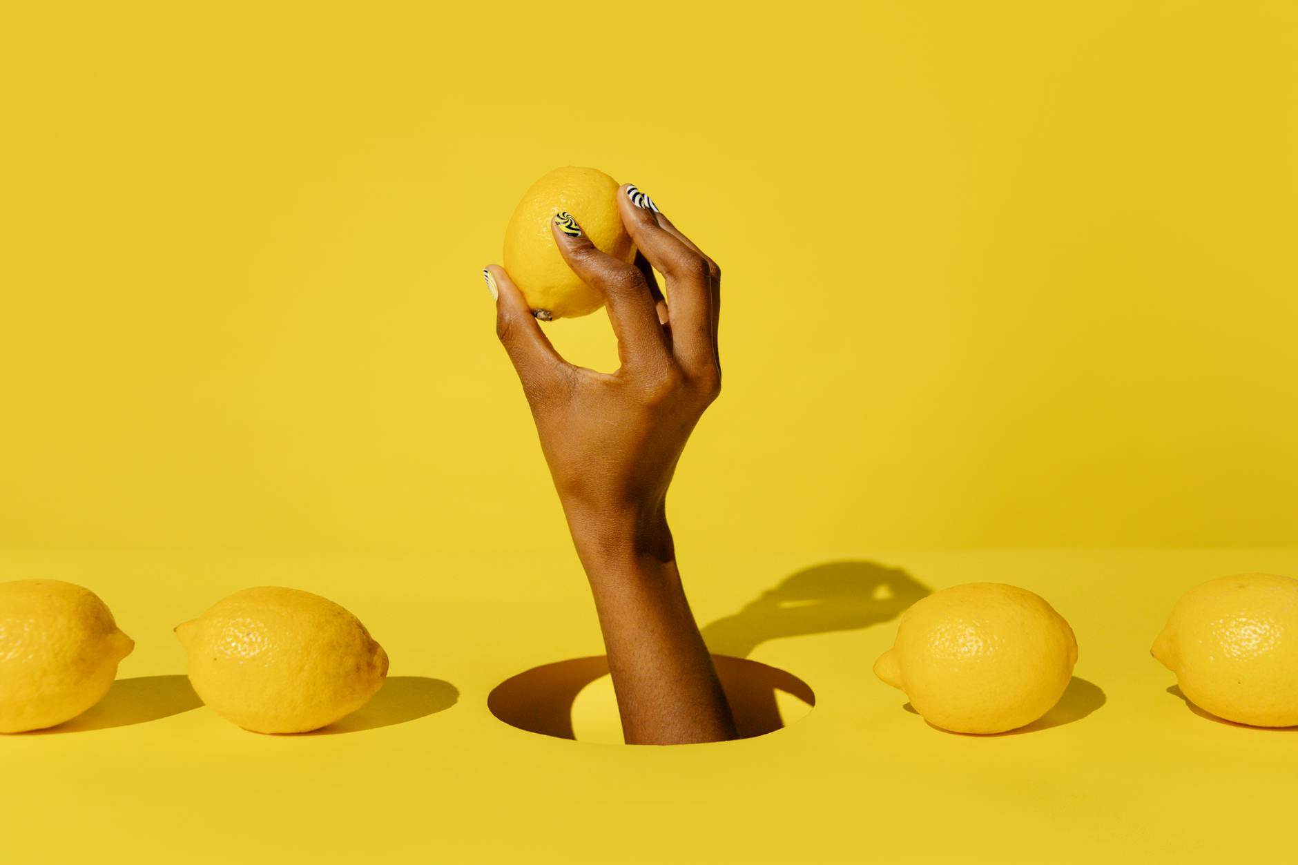 A hand holding a fresh lemon against a vivid yellow background, conveying revival and renewal after physical therapy.
