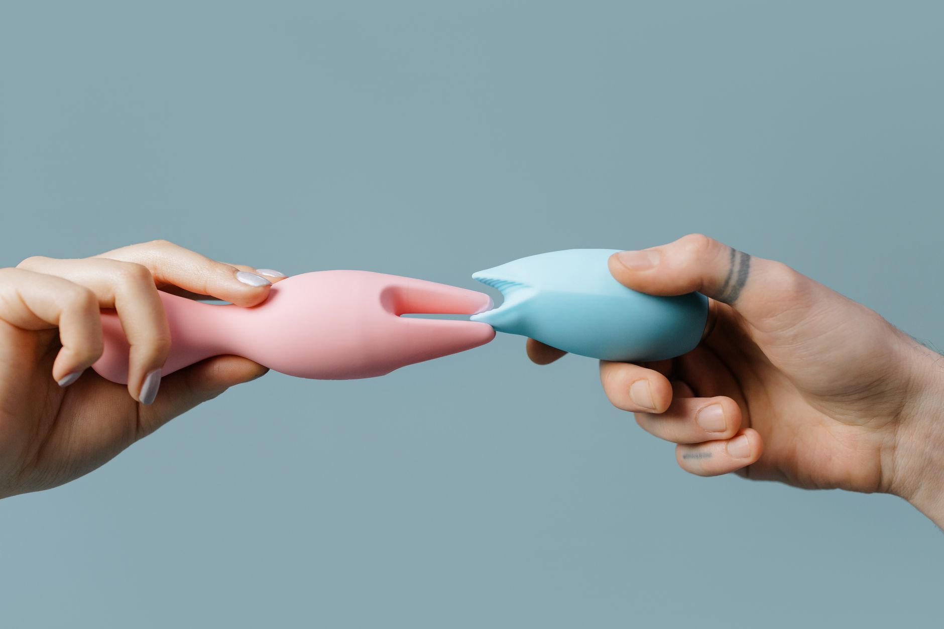 Close-up of hands holding a sleek blue vibrator against a purple background, representing intimate reconnection.