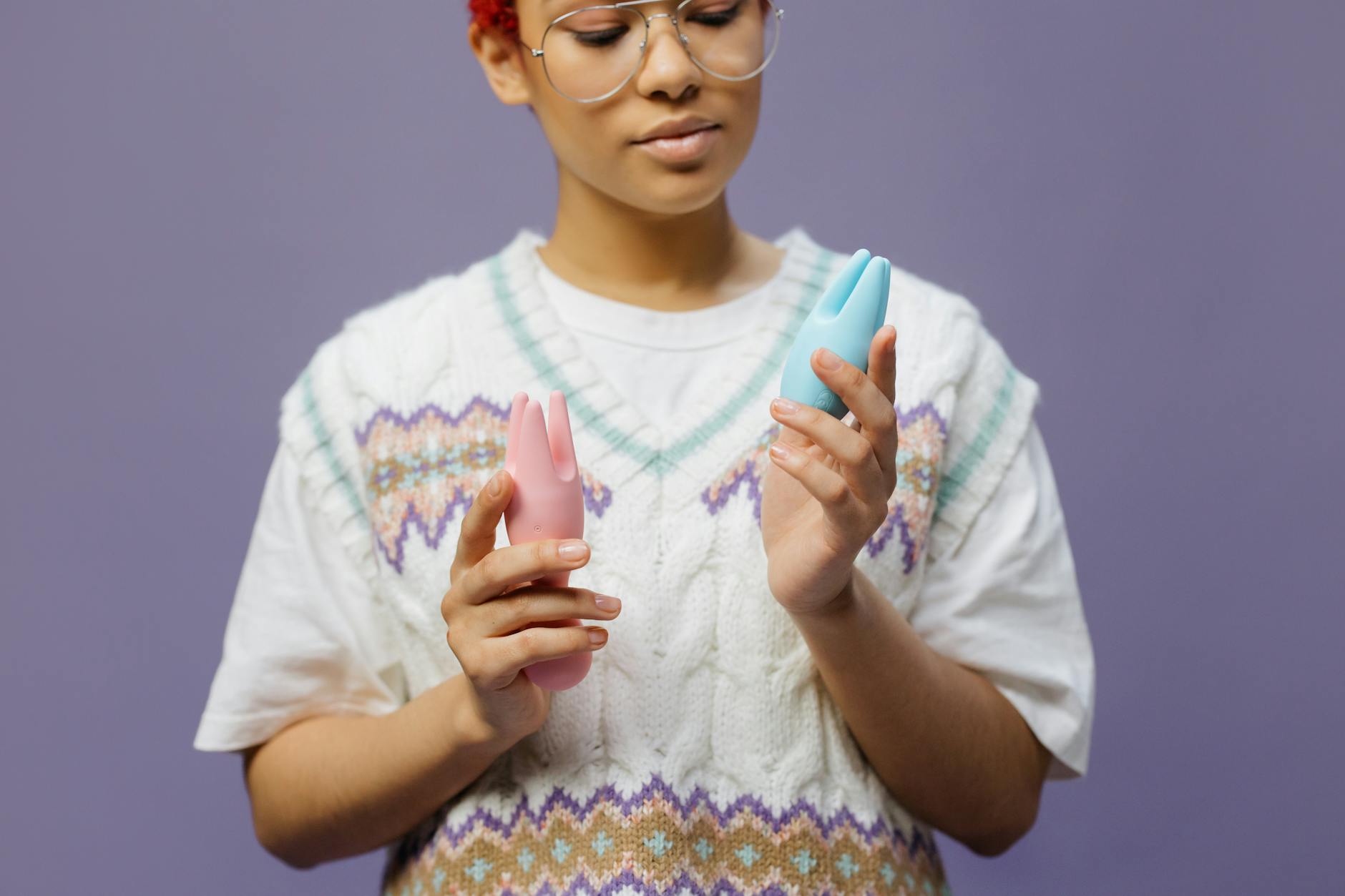 Person holding a blue silicone vibrator against a solid background, symbolizing self-care and sexual wellness