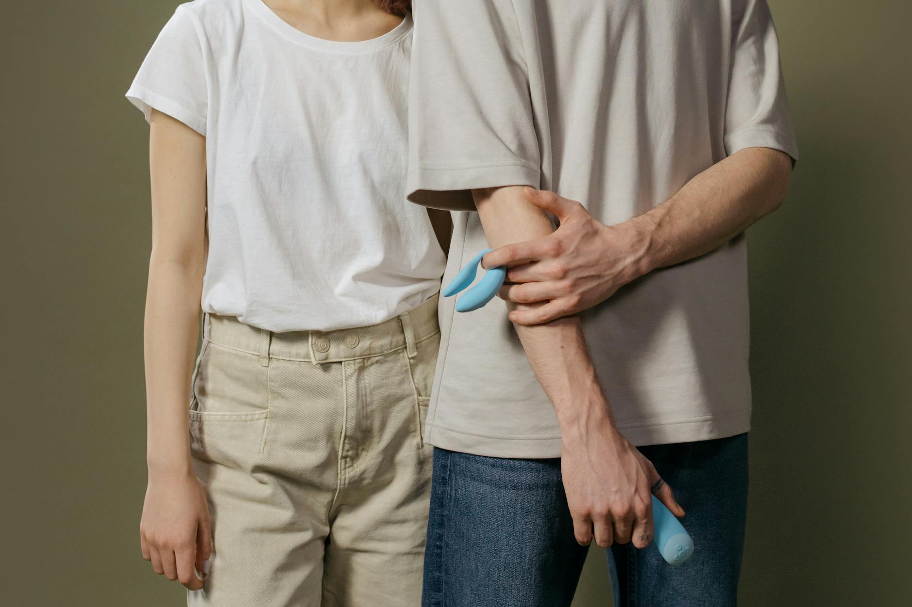 A young couple standing together indoors, holding a vibrator, symbolizing modern intimacy and communication