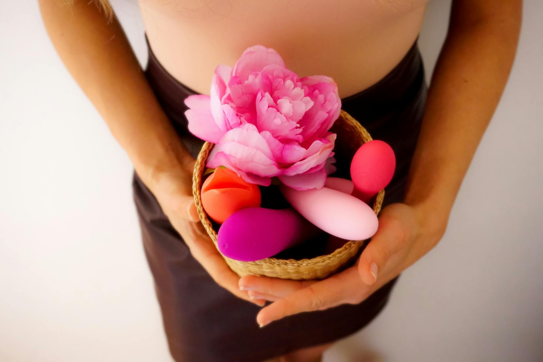 A hand holding a lemon-colored vibrator against a soft background